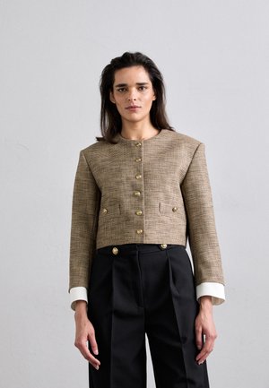 Cropped, woven blazer in brown check pattern with gold buttons, featuring a round neckline and long sleeves with white cuffs. Paired with black trousers.