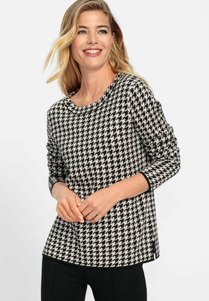 Black and white houndstooth-patterned long-sleeve top with a round neckline and solid black trim, featuring a relaxed fit and side slits.