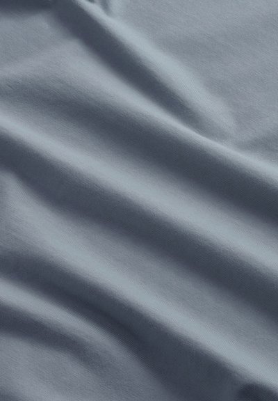 Tissu bleu clair doux avec des plis légers et une texture lisse, montrant des ombres subtiles et des reflets.