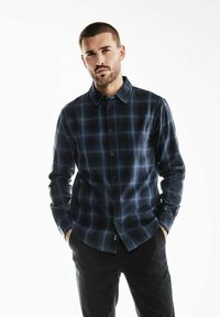 Camicia a maniche lunghe a scacchi in blu scuro e nero, realizzata in tessuto morbido. Presenta un colletto button-down e chiusura frontale con bottoni.