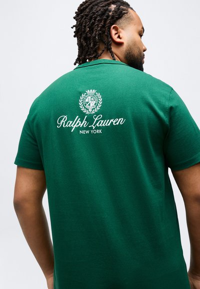 Άνδρας με πλεκτά μαλλιά που φοράει πράσινο πόλο μπλουζάκι με λευκό λογότυπο και έμβλημα "Ralph Lauren New York" τυπωμένα στην πλάτη.