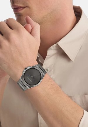 Orologio in acciaio inox silver con quadrante rotondo nero e accenti blu sulle lancette. Presenta un cinturino a maglie e un design minimalista.