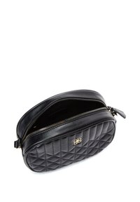 Bolso de cuero negro acolchado con un logotipo dorado, cierre de cremallera y forma redondeada. El interior está forrado con un patrón oscuro.
