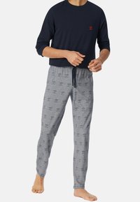 Donkerblauw overhemd met lange mouwen en een klein rood logo; lichtgrijze pyjamabroek met patroon en trekkoord. Katoenen stof, relaxed fit, casual ontwerp.
