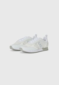 Adidași albi din material textil cu panouri din plasă și sintetic, cu vârf rotund, talpă plată și accente gri deschis. Au sireturi și un maner pentru a fi ușor de încălțat.