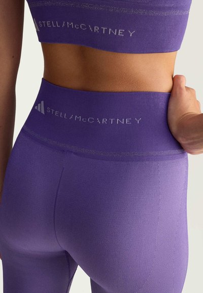 Purple activewear set featuring a ribbed texture. The high-waisted leggings have a logo waistband and a fitted design, with seamless stitching.