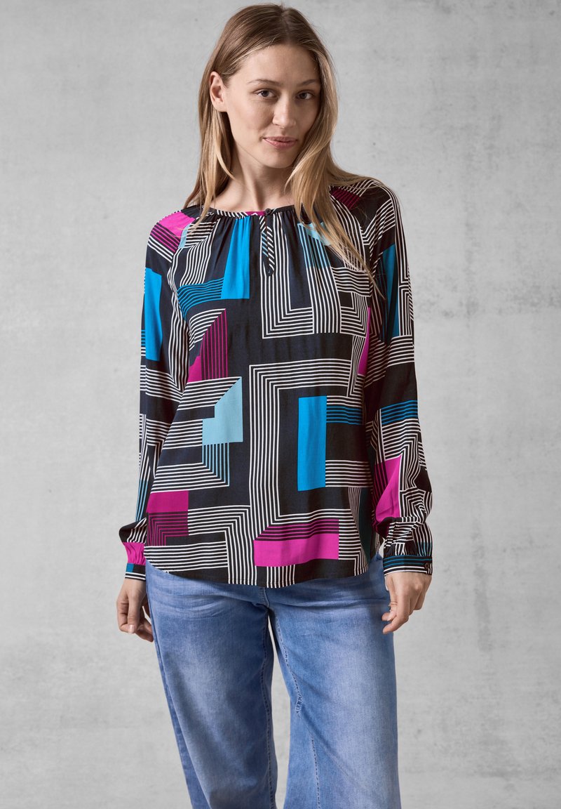 Svart blus med färgglada geometriska mönster i blått och magenta, med rund halsringning och långa ärmar, tillverkad av lättviktsmaterial.