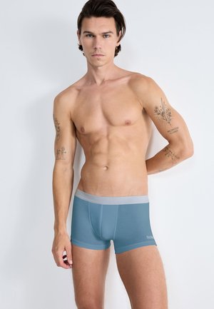 Boxershorts i ett mjukt, ljust blått tyg med en grå midjeresård. Har en figurnära design och slät textur, lämpliga för vardagsbruk.
