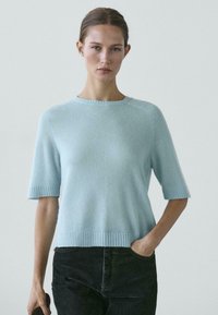 Maglione azzurro chiaro a maniche corte con scollo rotondo, polsini e orlo a coste. Texture morbida e vestibilità rilassata con cuciture sottili.
