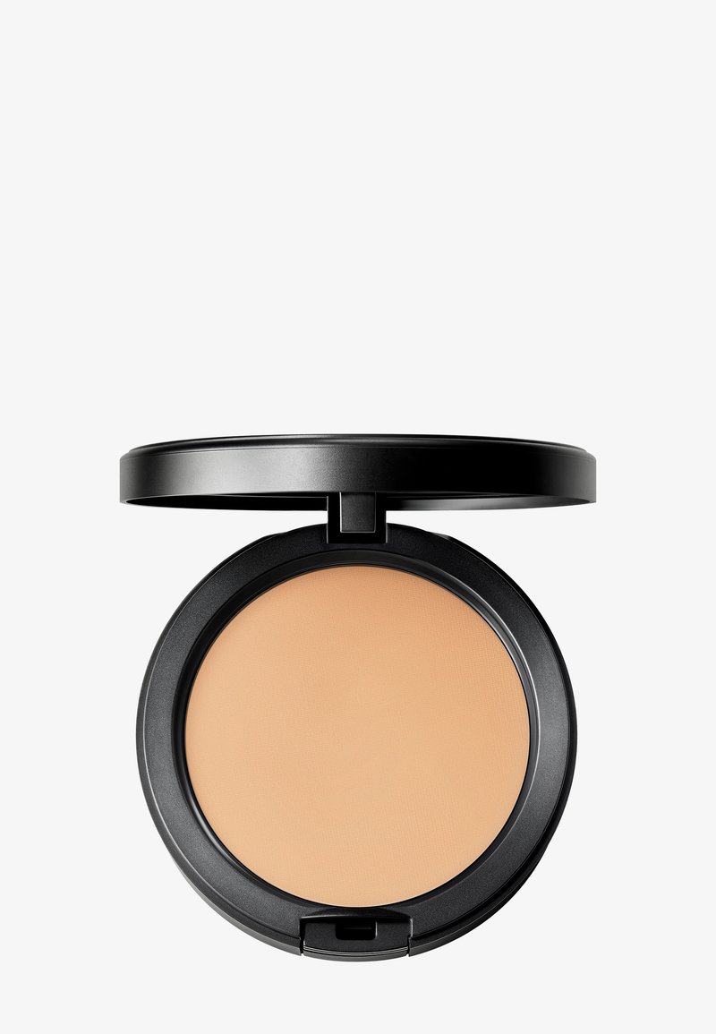 Étui compact noir avec poudre pressée beige et couvercle ouvert sur un fond gris clair.