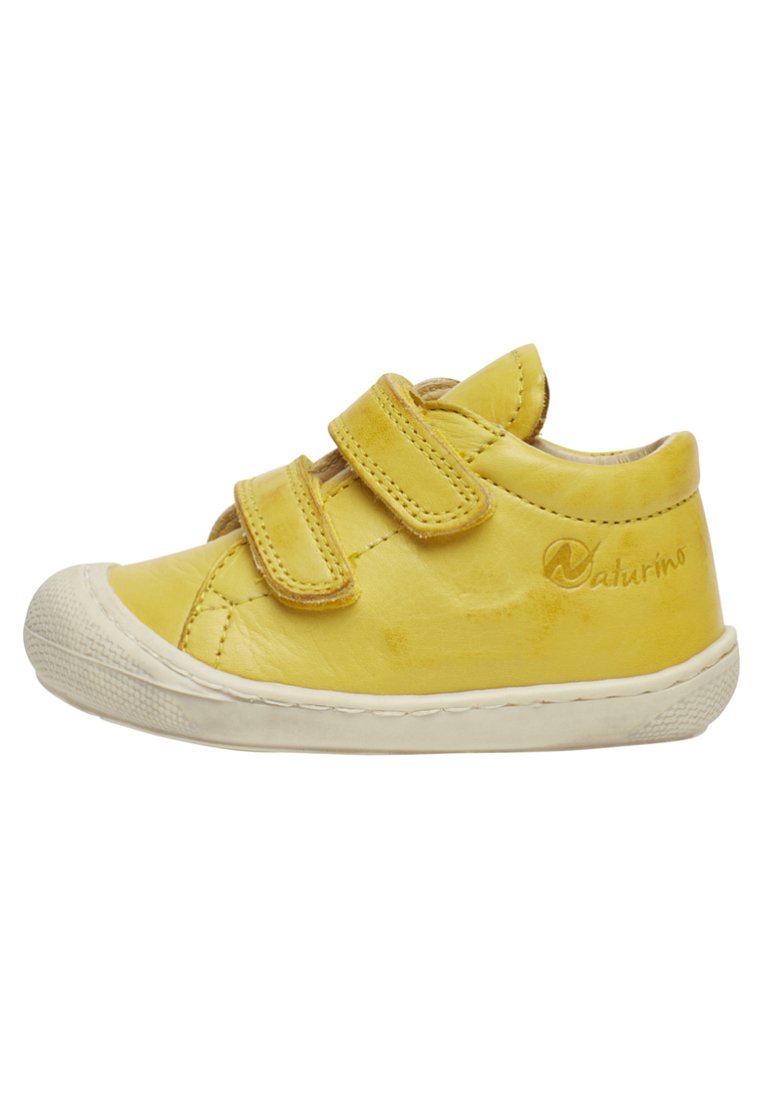 Gelbe Ledersneaker für Kleinkinder mit zwei Klettverschlüssen, abgerundeter Spitze, weißer Gummisohle und dezentem Branding an der Seite.