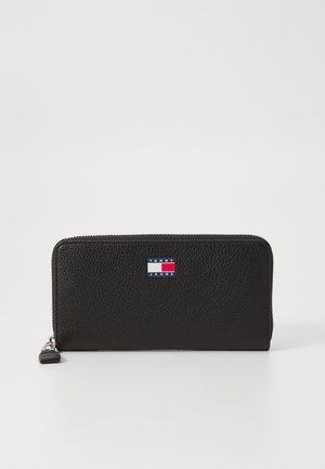 Black leather wallet with a textured finish, featuring a blue, white, and red logo patch on the front and a zip-around closure.