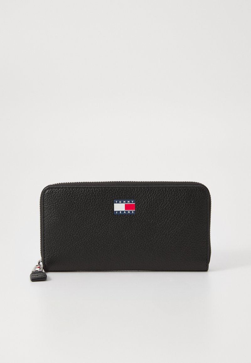 Black leather wallet with a textured finish, featuring a blue, white, and red logo patch on the front and a zip-around closure.