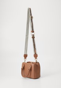 Kohvatanane nahk käekott, kuldse riistvara, kahe lühikese käepideme ja halli logoga pika reguleeritava rihmaga. Ruudukujuline, sile tekstuur.