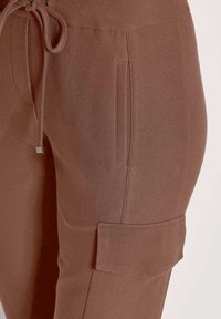 Bruine cargo-broeken met een gladde textuur, voorzien van een trekkoord in de taille en een zijzak met een vierkante klep.