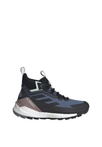 Chaussure de trail montante avec des couleurs noir, gris et violet, semelle texturée, languettes de tirage, et marquée "TERREX" sur le talon.