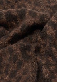 Tela de colores marrón y negro con un acabado suave y texturizado, que presenta un caído ondulado y una combinación de tonos claros y oscuros.