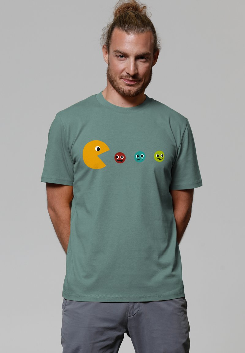 Green cotton t-shirt featuring a large yellow Pac-Man graphic and four colorful ghost characters in red, blue, turquoise, and green.