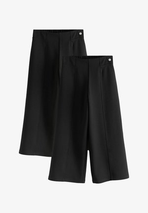 Dos pares de pantalones culotte negros de pierna ancha con detalles de costura frontal y botones plateados en la cintura.