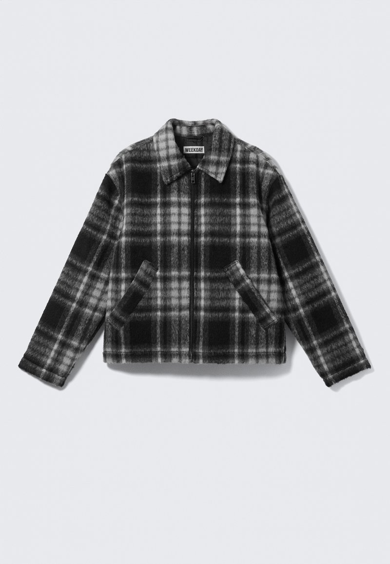 Veste zippée à carreaux noirs et gris avec col et deux poches avant, étalée à plat sur un fond blanc.