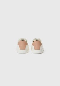 Sneakers bianchi con una finitura liscia e accenti rosa sul retro, caratterizzati da un design minimalista e elementi testurizzati per una migliore aderenza.