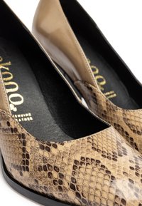 Ballerine beige con un motivo in finta pelle di serpente a trama, punta rotonda e un interno nero liscio con dettagli del logo dorato.