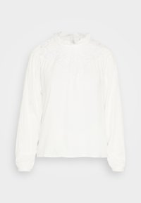 Blouse blanche à manches longues avec un empiècement en dentelle, un col froncé et un tissu doux. La coupe est loose avec des poignets froncés au niveau des manches.