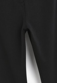 Pantalons de sport noirs en tissu lisse, avec une coupe ajustée et une jambe fuselée, et un design minimaliste.