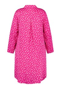 Chemise rose à motif avec un col, des manches longues et une coupe ample. Le design comprend de petites formes arrondies dans différentes nuances de rose.