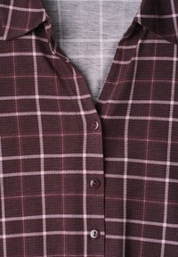 Chemise à carreaux bordeaux boutonnée avec col, présentant un motif à carreaux composé de fines lignes blanches.