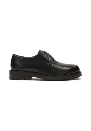 Zapato de vestir de cuero negro con punta redondeada, diseño de cordones y suela de goma texturizada. Acabado suave y detalle de costura mínima.