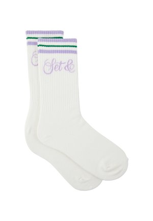 Weiße Crew-Socken mit gerippter Struktur, lila und grüne Streifen oben und lila kursiver Schrift nahe der Manschette.