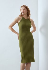 Green ribbed knit dress with a sleeveless design and a high neckline, featuring vertical stripes and a fitted silhouette.