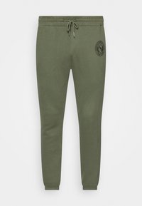 Olivgrüne Sweatpants aus Baumwollmischung, mit elastischem Bund und Kordelzug sowie einem runden Logoaufdruck am linken Oberschenkel.