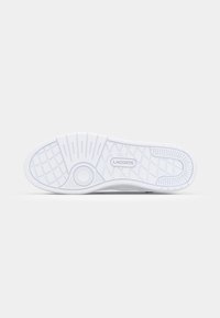 Suela de zapatilla de goma blanca con un patrón de cuadrícula texturizado y un acento circular, con el logo "LACOSTE" en la entresuela.