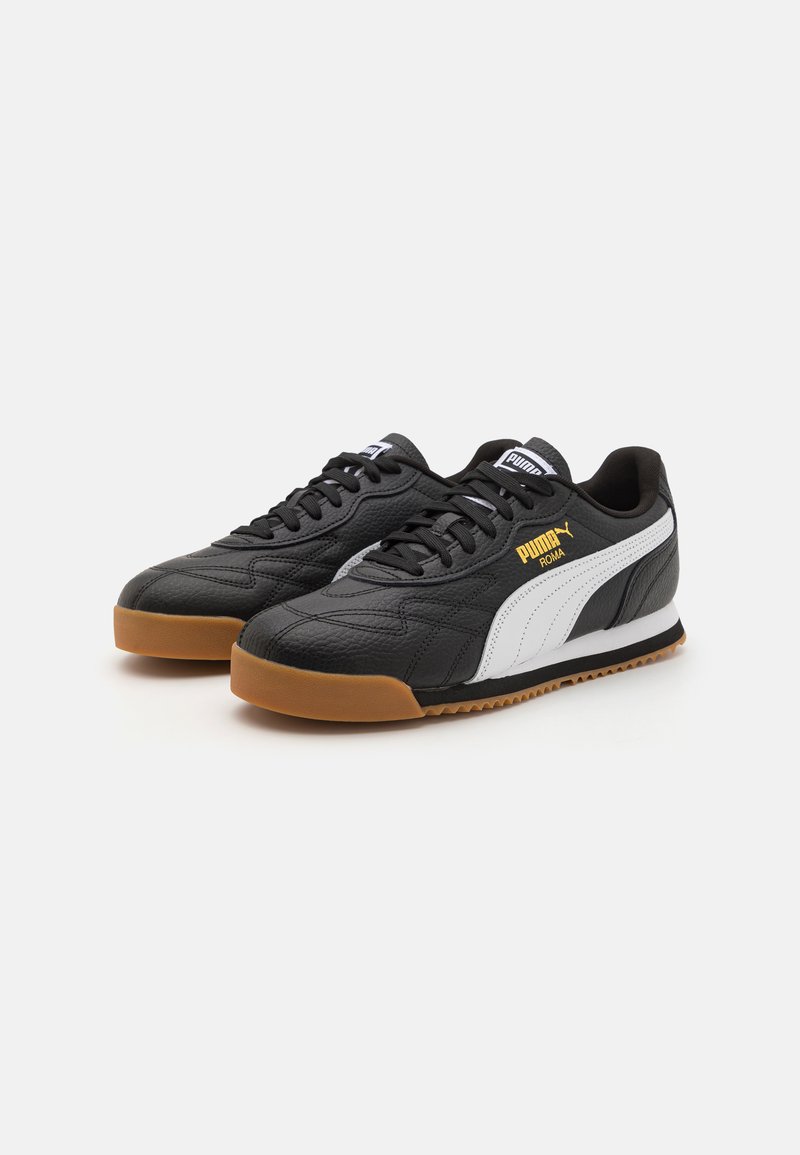 Baskets en cuir noir et blanc avec une tige texturée, semelle en caoutchouc, et lacets noirs contrastants ; arbore le logo Puma en or.