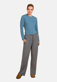 Langsleeve blauwe bovenstuk gecombineerd met gestreepte, wijde broek in blauw, oranje en crème. De broek heeft zakken en een trekkoord in de taille.