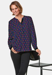 Multikleurige blouse met een geometrisch patroon met ronde vormen, zwarte manchetten en een V-hals, gemaakt van lichtgewicht stof.