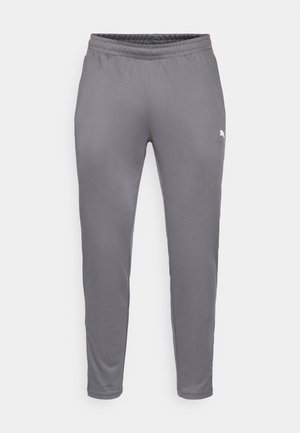 Grå træningsbukser med en strækbar talje, tapered ben og et lille hvidt logo på venstre lår. Glat tekstur, letvægtsmateriale.