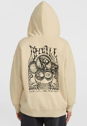 Hoodie beige avec un grand motif graphique noir dans le dos, comprenant des motifs circulaires et du texte. Il possède une poche avant et un capuchon à cordon.