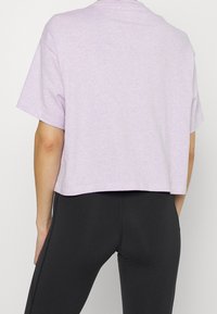 Jasnofioletowy krótki T-shirt z krótkim rękawem, o miękkiej fakturze i okrągłym dekolcie, w zestawie z czarnymi dopasowanymi legginsami.