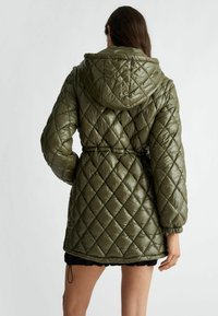 Giubbotto imbottito trapuntato verde oliva con cappuccio, vita arricciata e polsini elastici, con una finitura lucida e testurizzata.