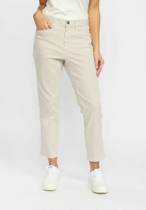 Stribede beige bomuldsbukser med slim fit, forkortet længde, forlommer og knaplukning. Sammen med hvide sneakers.