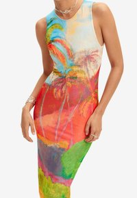 Farverig ærmeløs kjole i strækbart stof med et livligt tropisk print med palmer, der blander nuancer af rød, blå, grøn og gul.