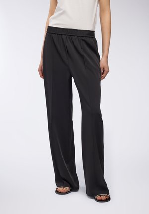 Pantaloni neri, di taglio ampio, realizzati in tessuto leggero con vita elastica e pieghe laterali. Presentano una superficie liscia e gambe larghe.