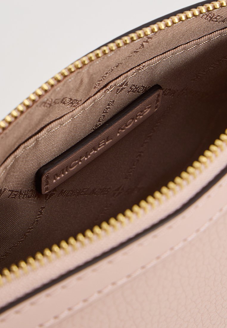 Roze leren etui met een gouden rits, met een gladde textuur en een merkgebonden bruine stoffen binnenkant. Kleine interne merklabel zichtbaar.