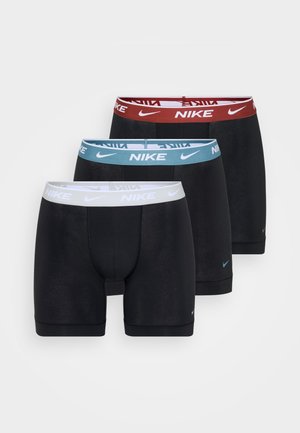Trzy pary czarnych bokserków Nike z elastycznymi paskami w kolorach czerwonym, jasnoniebieskim i białym, z wyraźnie widocznym logo Nike.