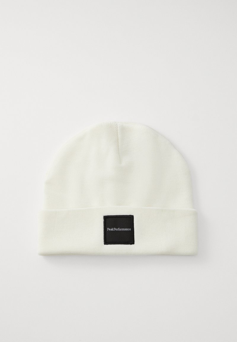 Gorro de malha branco com dobra na bainha, apresentando um rótulo quadrado preto com texto branco, feito de um tecido macio para aquecer.
