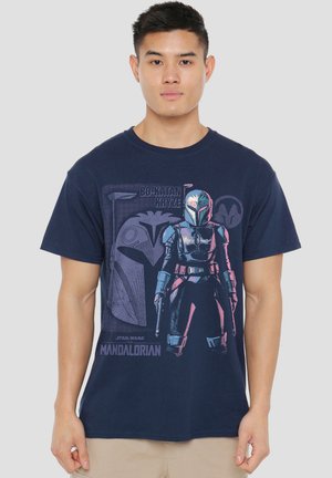 Young man wearing a navy blue t-shirt featuring a graphic of Bo-Katan Kryze from Star Wars The Mandalorian.