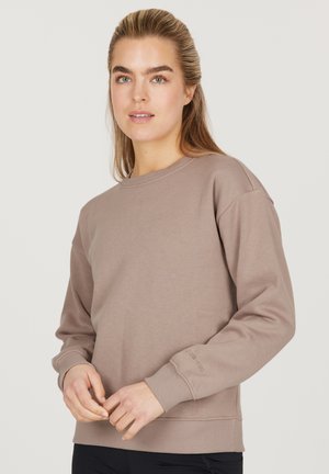 Lysebrun sweatshirt med rund hals, ribbede ærmer og nederkant. Fremstillet af blødt stof med minimal branding på ærmet.